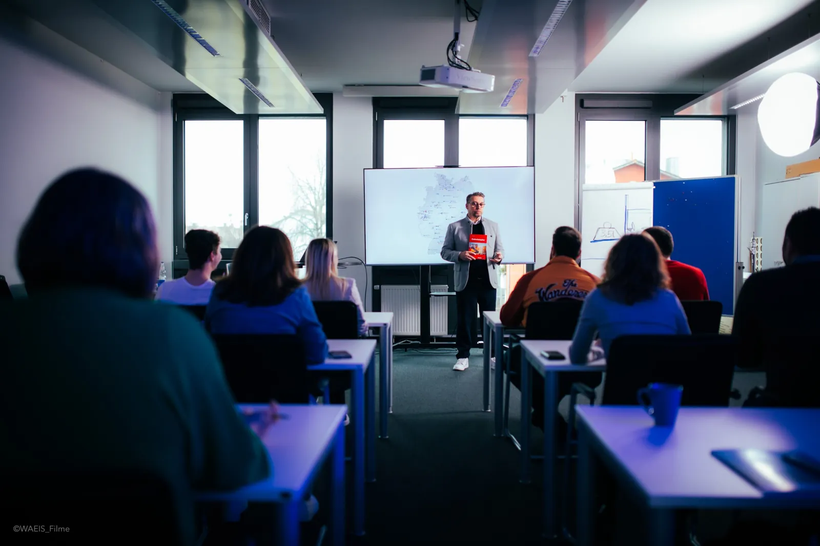 Dreh in einem Schulungsraum, Referent vor Teilnehmenden